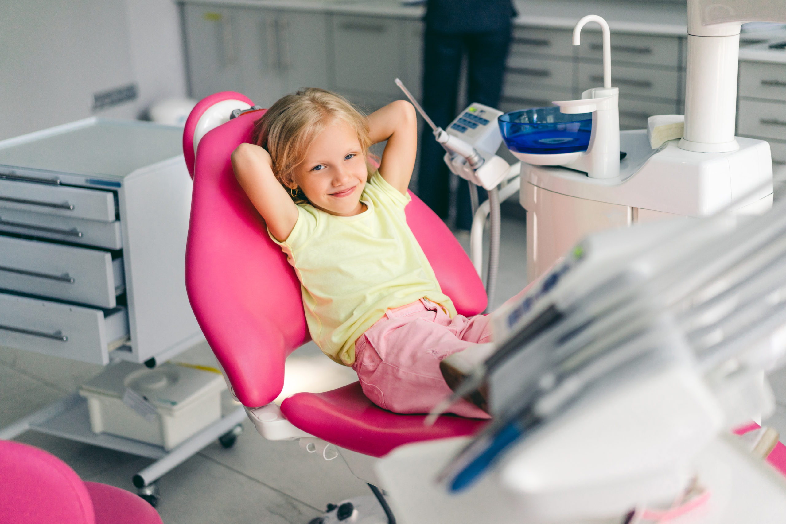 smiling kid looking at camera a while sitting in chair at dentist office