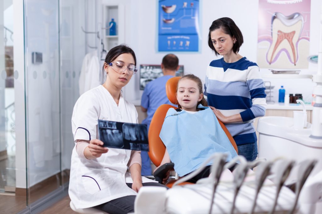 Dentist examining little kid radiography sitting on chair
