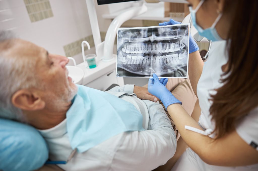 Professional dental doctor and a patient looking at x-ray image