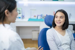 Caucasian beautiful girl talks and consult with Asian female dentist in dental clinic.